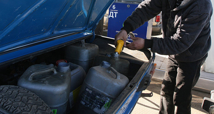 Водитель наливает бензином канистры в багажнике. Архивное фото